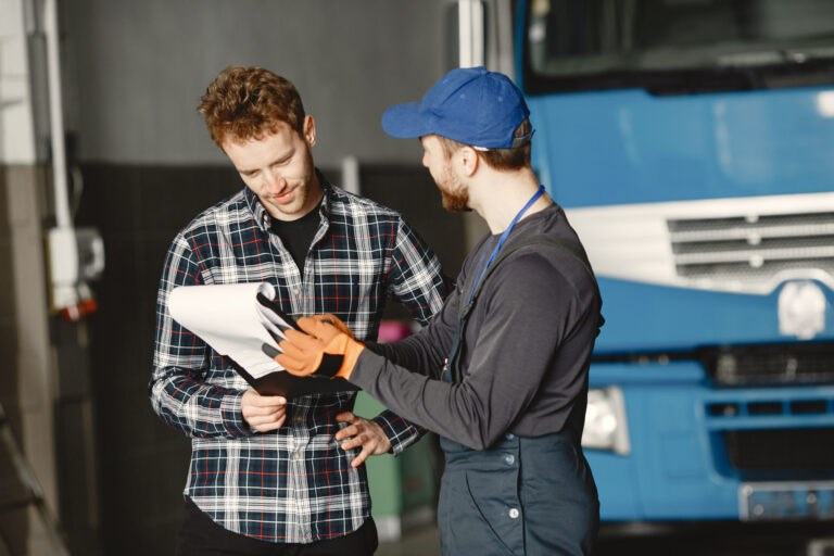 Two young men discuss work issues in garage Commercial driver and officer reviewing a CHP roadside inspection checklist before starting the inspection.